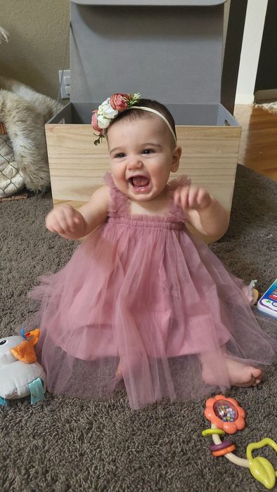 Elle Pruitt at nine months old in pink tulle dress, laughing
